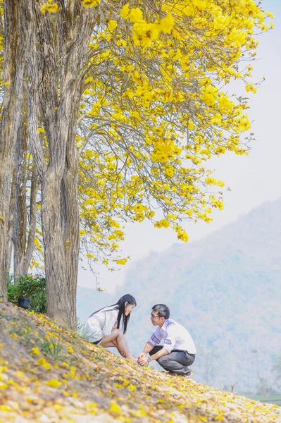 asia happy young couple sitting on yellow tree