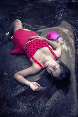 Asya güzel genç seksi kız kayanın üzerinde uzanmış 