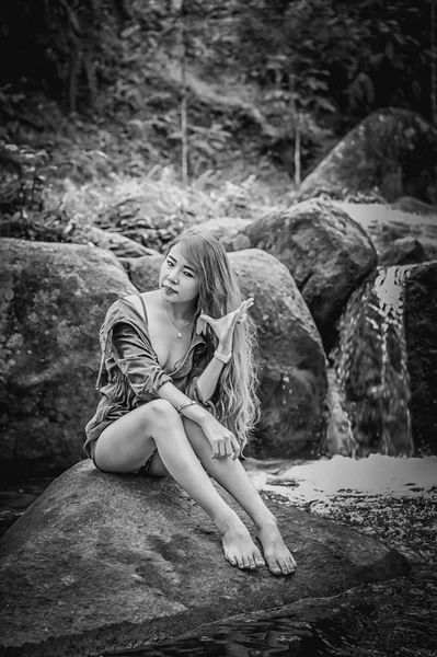 Ασία όμορφη νεαρή κοπέλα που κάθεται σε βράχο — Φωτογραφία Αρχείου
