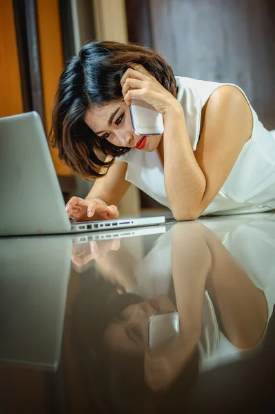 Ásia mulher usando telefone inteligente e laptop deitado no chão — Fotografia de Stock