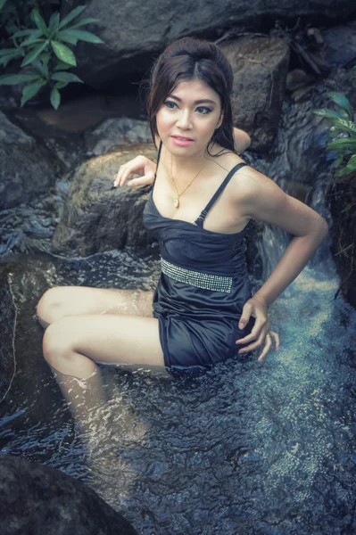 Asia Hermosa joven sentada en la caída del agua — Foto de Stock