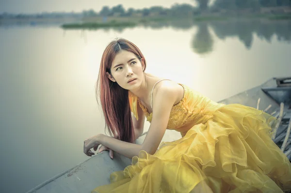 Sarı elbiseli Asya güzel kadın oturup teknede — Stok fotoğraf
