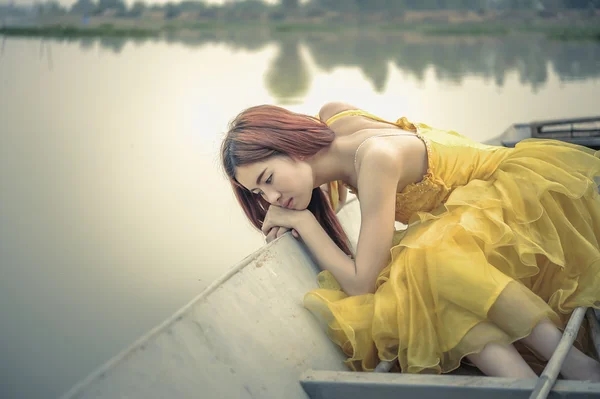 黄色のドレスで美しいアジア女性が船の上に座る — ストック写真