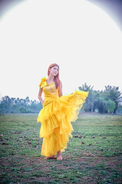 Asia Hermosa mujer en vestido amarillo de pie en el campo — Foto de Stock