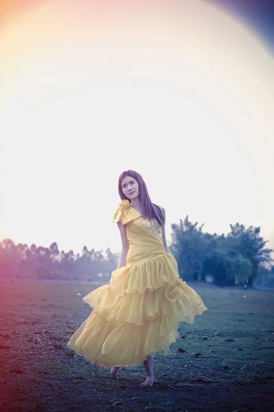 Азія красива жінка в жовте плаття стояти на полі — стокове фото