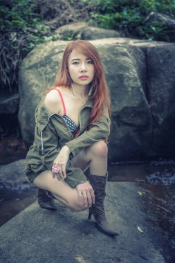 Kayanın üzerinde oturan Asya güzel genç kız