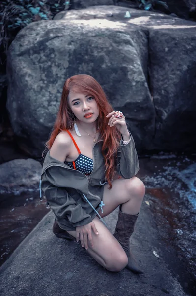 Asia Hermosa joven sentada en la roca — Foto de Stock
