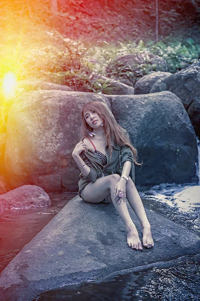 Asia Hermosa joven sentada en la roca — Foto de Stock
