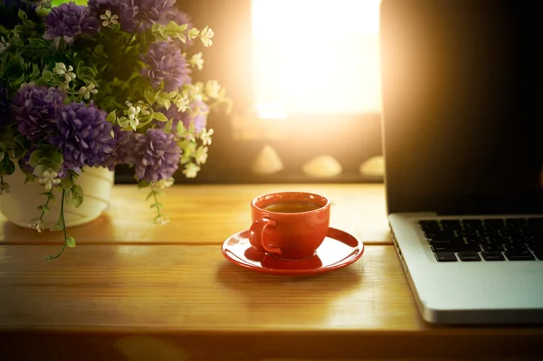 Kopp kaffe och laptop på trä skrivbord i café — Stockfoto