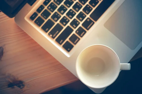 Portátil y taza de café blanco vacío en la mesa de madera — Foto de Stock