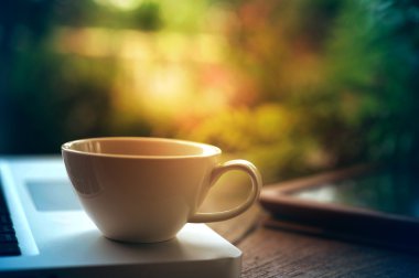 Laptop tablet ve ahşap masa üzerinde beyaz kahve fincanı