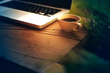 Beyaz fincan kahve ve ahşap masa üstünde laptop. 