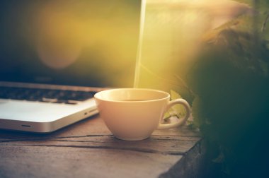 Beyaz fincan kahve ve ahşap masa üstünde laptop. 