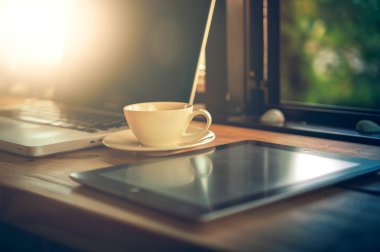 Laptop tablet ve ahşap masa üzerinde beyaz kahve fincanı