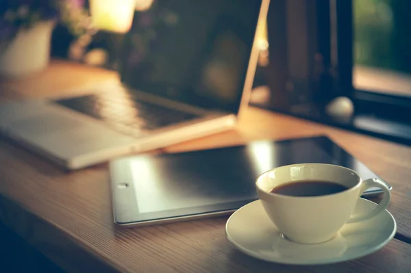 ラップトップ タブレットと木製のテーブルの上の白いコーヒー カップ — ストック写真