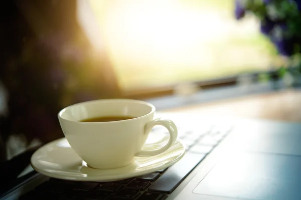 Beyaz fincan kahve ve ahşap masa üstünde laptop. — Stok fotoğraf