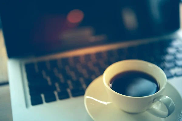 木製のテーブルの上にコーヒーとノートパソコンのカップ. — ストック写真
