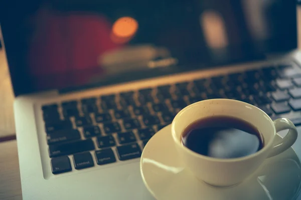 Witte kopje koffie en laptop op houten tafel. — Stockfoto