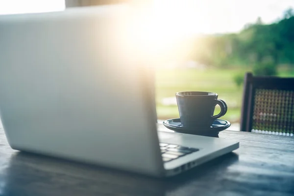 sıcak kahve fincanı ve ahşap masa üstünde laptop