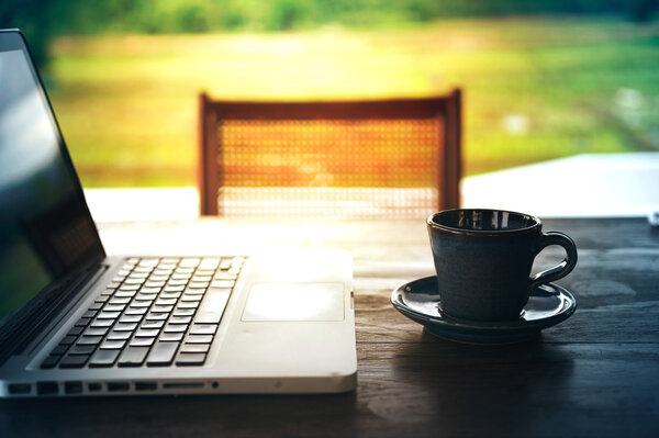 hot coffee cup and laptop on wood table