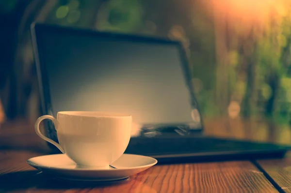 ホット コーヒー カップと木製のテーブルの上のノート パソコン — ストック写真
