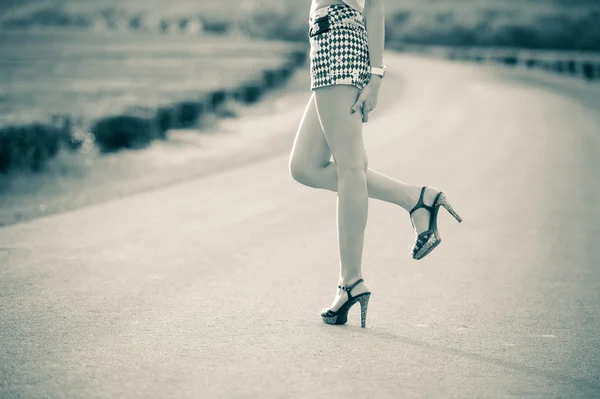 Piękna kobieta nogi w wysokich obcasach na drodze — Zdjęcie stockowe