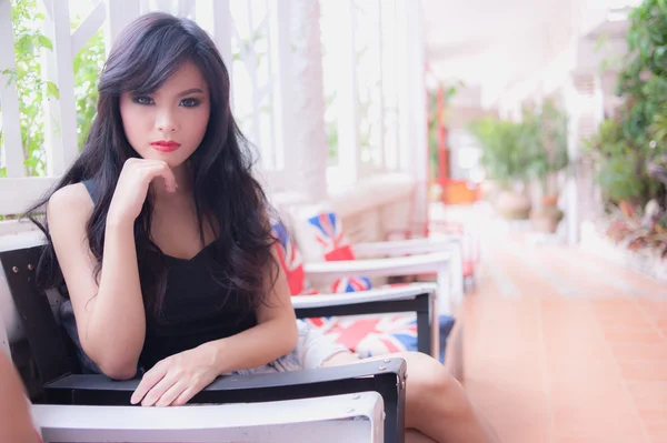 Sexy young girl sitting on chair in cafe — Stock Photo, Image