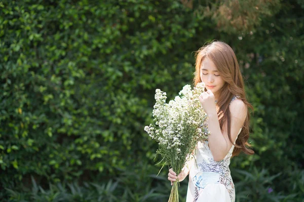 Asia bella ragazza è holding fiore su il verde prato . — Foto Stock
