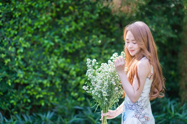 Όμορφο κορίτσι της Ασίας κρατώντας το λουλούδι στο πράσινο λιβάδι. — Φωτογραφία Αρχείου