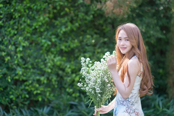 Asya güzel kız üzerinde yeşil çayır çiçek tutuyor. — Stok fotoğraf
