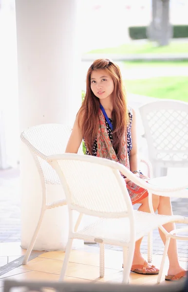 Ásia jovem mulher sentada na cadeira branca moderna — Fotografia de Stock