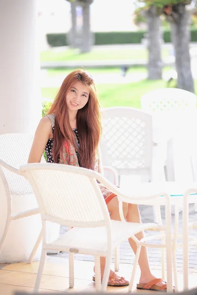 Ásia sorriso jovem mulher sentada na cadeira branca moderna, relaxante — Fotografia de Stock