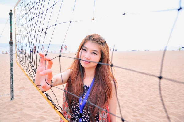 Asia fiatal nő mögött röplabda nettó, sport conce a strandon — Stock Fotó