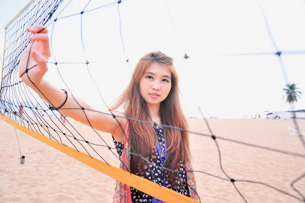 Asiatisch junge frau hinter volleyballnetz am strand, sport conce — Stockfoto