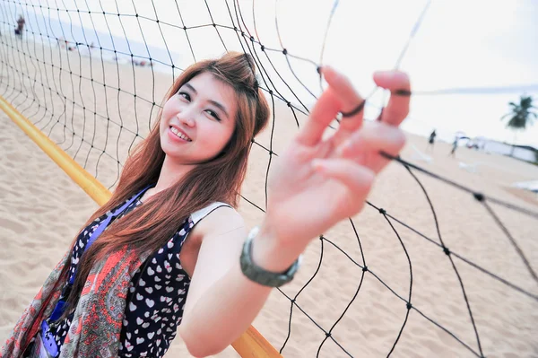 Retrato da Ásia jovem mulher perto de rede de voleibol na praia — Fotografia de Stock