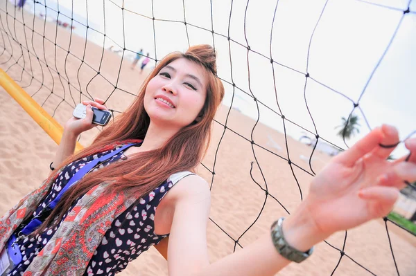 Retrato da Ásia jovem mulher perto de rede de voleibol na praia — Fotografia de Stock