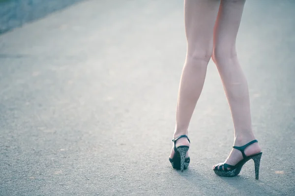 Mooie vrouw benen in hoge hak schoenen op de weg — Stockfoto