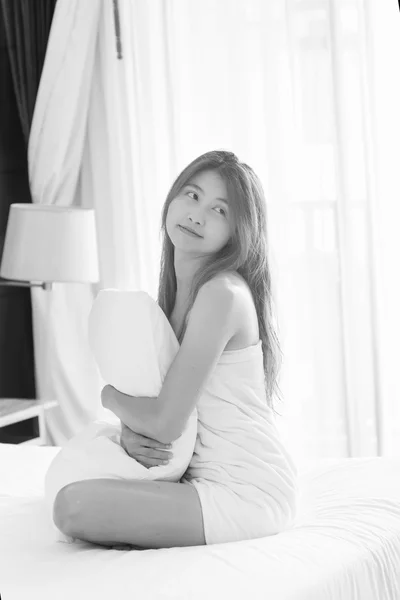 白毛巾的亚洲女人抱着枕头坐在床上 — 图库照片