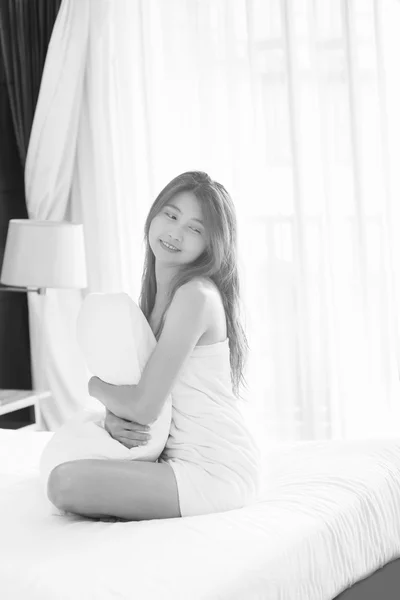 白毛巾的亚洲女人抱着枕头坐在床上 — 图库照片