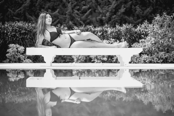 Bikini asia woman on sunbath longue by the pool — Stock Photo, Image