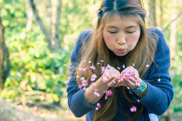 Asien kvinna blåser en blomma i handen — Stockfoto