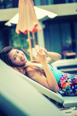 Tembel Yüzme Havuzu yakınındaki üzerinde akıllı telefon kullanan güzel kadın