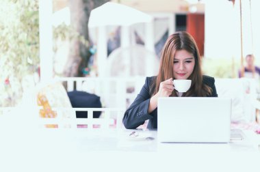  Dizüstü bilgisayar ve kahve kafede oturan Asya genç iş kadını