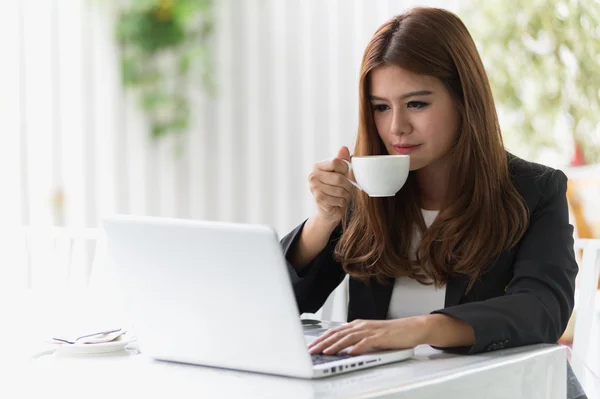 Asia joven mujer de negocios sentado en la cafetería con ordenador portátil y café — Foto de Stock