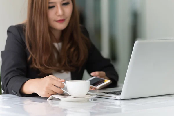 Asia joven mujer de negocios sentado en la cafetería caliente con el ordenador portátil y ho — Foto de Stock