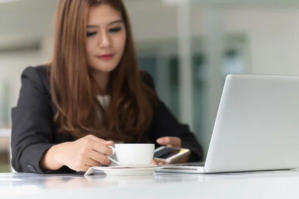 Asia joven mujer de negocios sentado en la cafetería caliente con el ordenador portátil y ho — Foto de Stock