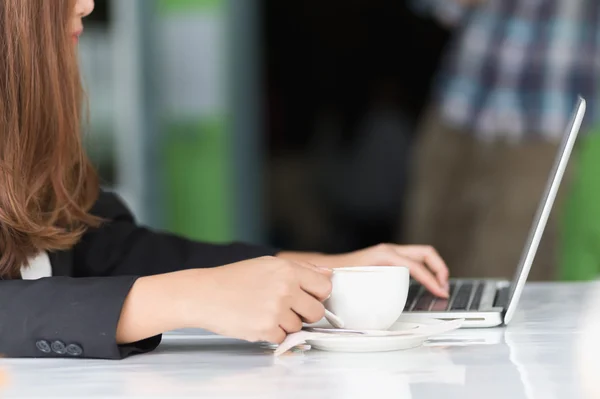 Asia joven mujer de negocios sentado en la cafetería caliente con el ordenador portátil y ho — Foto de Stock