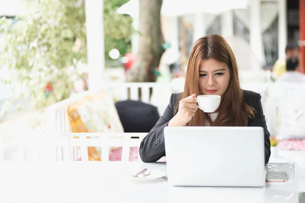 Asia joven mujer de negocios sentado en la cafetería con ordenador portátil y café — Foto de Stock
