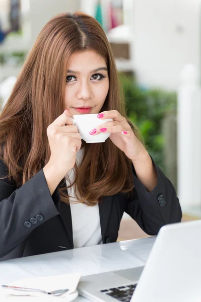 Asia joven mujer de negocios sentado en la cafetería con ordenador portátil y café — Foto de Stock