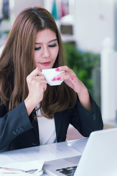 Asia joven mujer de negocios sentado en la cafetería con ordenador portátil y café — Foto de Stock